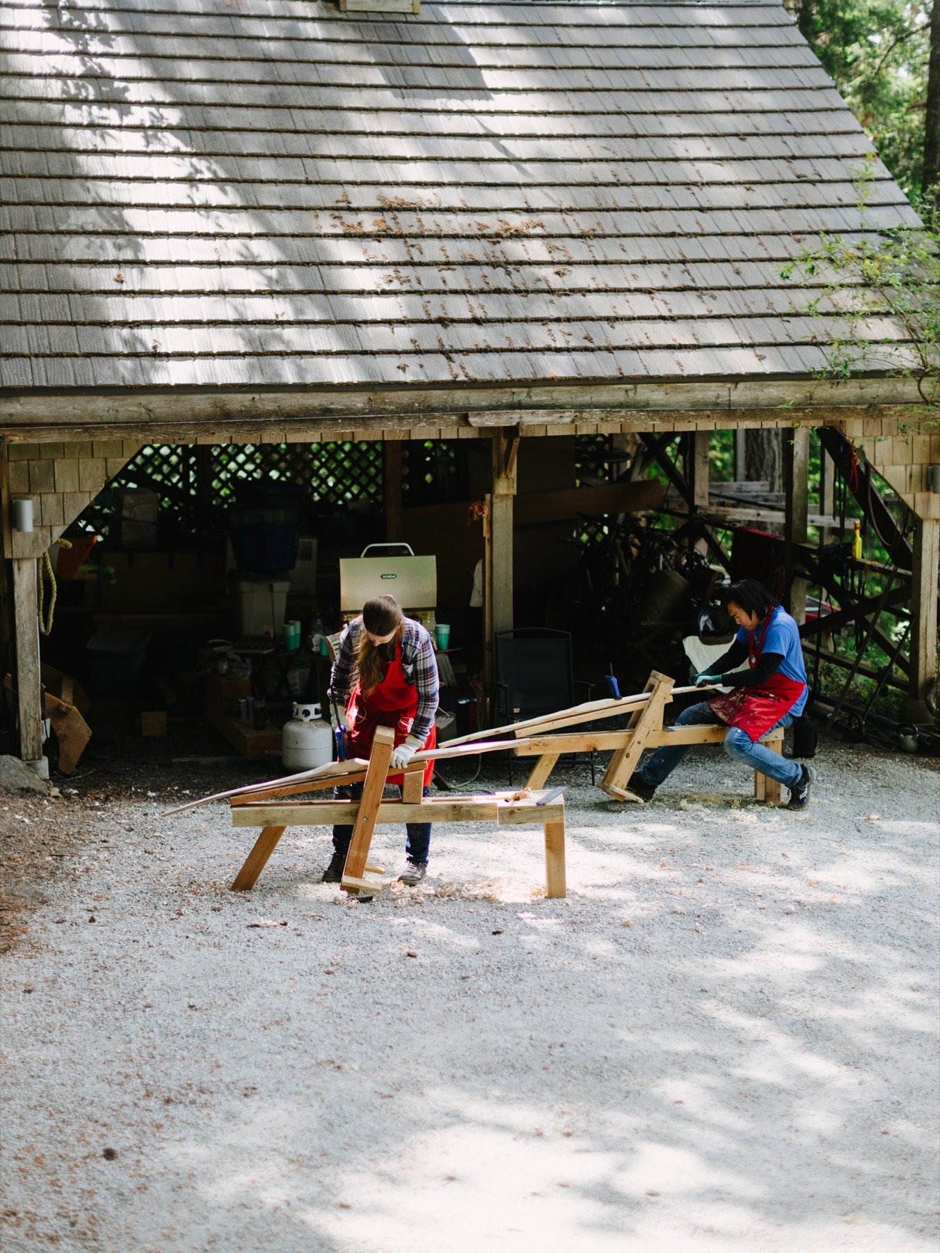 A participant leaning into a drawknife at a shaving horse.