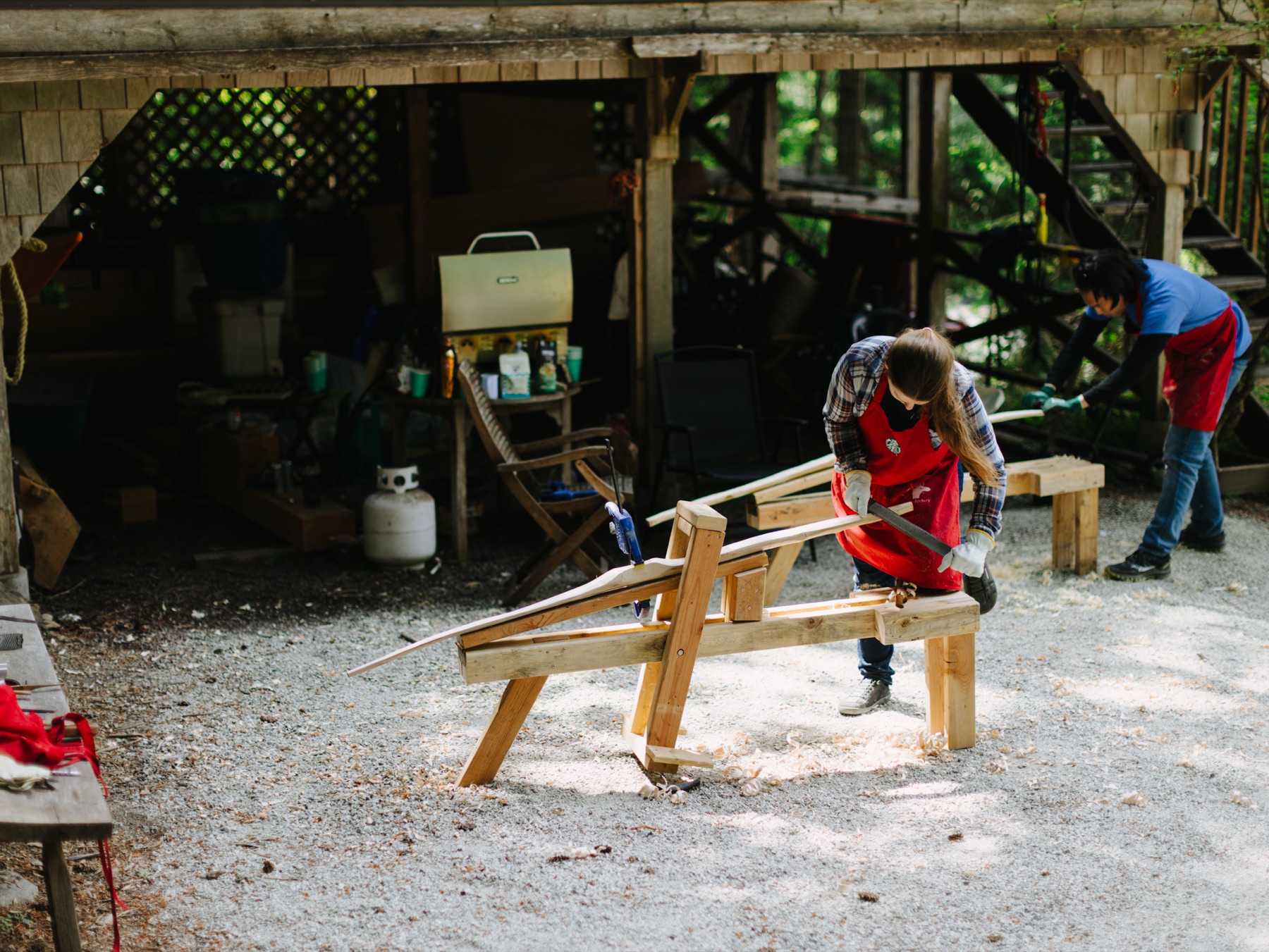 Workshop participants shaping bow staves on shaving horses outside the shop.